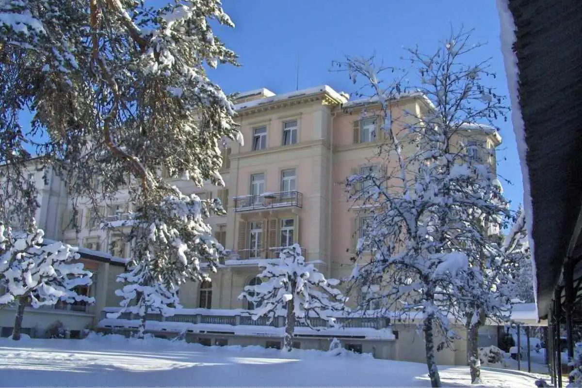 Waldhaus Flims Wellness Resort Hotel covered in a light dusting of snow on a clear day.