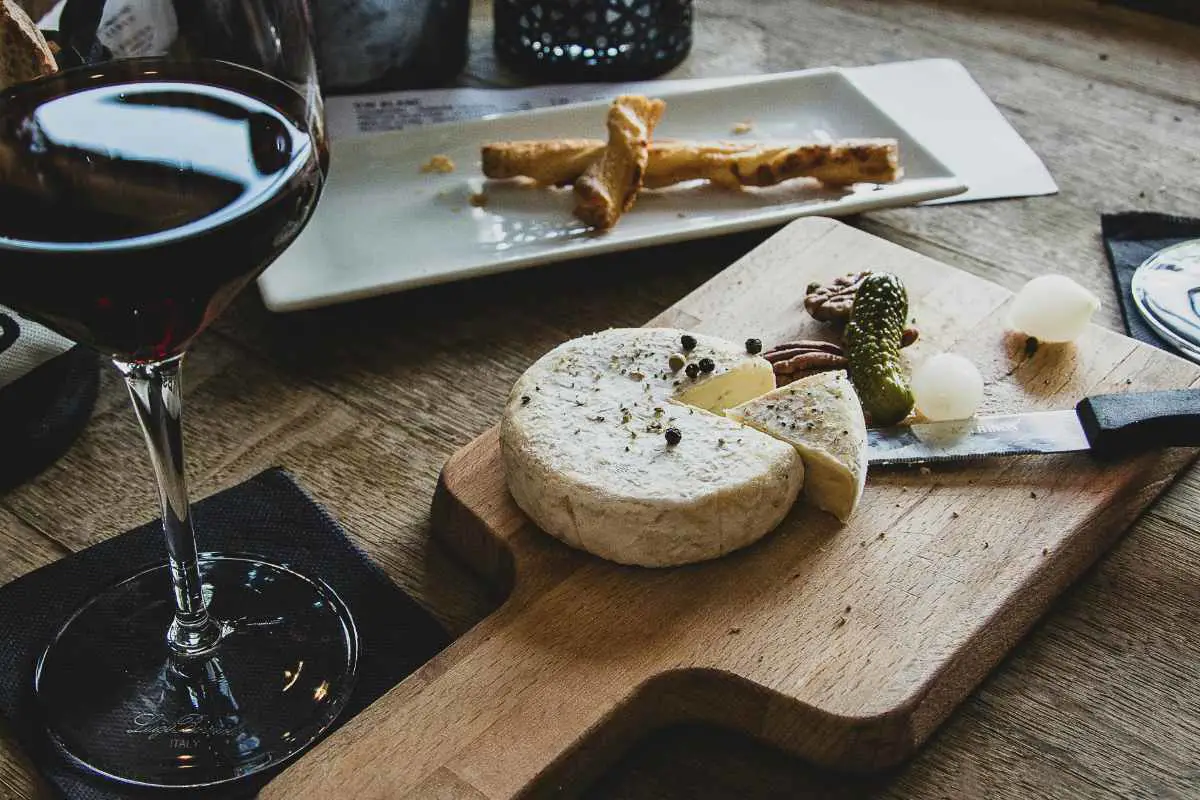 Swiss cheese presented on a board with wine and snacks. Photo by Camille Brodard from Unsplash